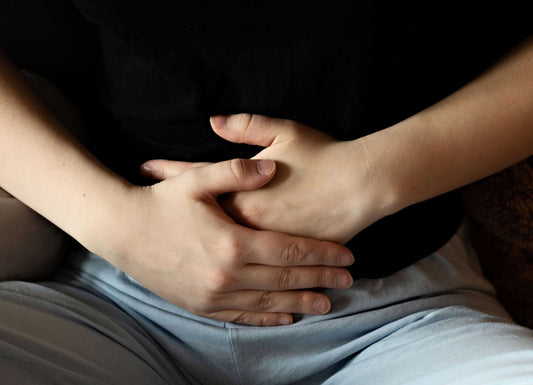 a zoomed-in picture of a person's stomach with both hands holding it to depict stomach pain. Diarrhea