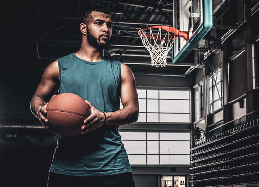 Picture of a man holding a basketball in front of a basketball hoop. Athletes/Top Performance