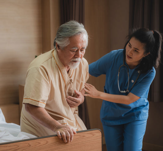 Picture of an elderly man with chest pain as a nurse helps him to bed Heart Disease