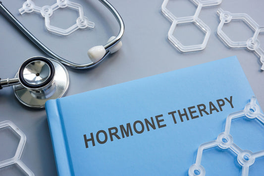 a picture of the top half of a blue book with the text "hormone therapy" on it. above the book, is the listening and chest piece of a stethoscope. scattered around are plastic molecules Hormone Replacement Therapy