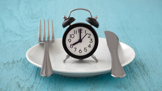 Image of a clock sitting on a plate with a knife and fork on either side of it. Fasting