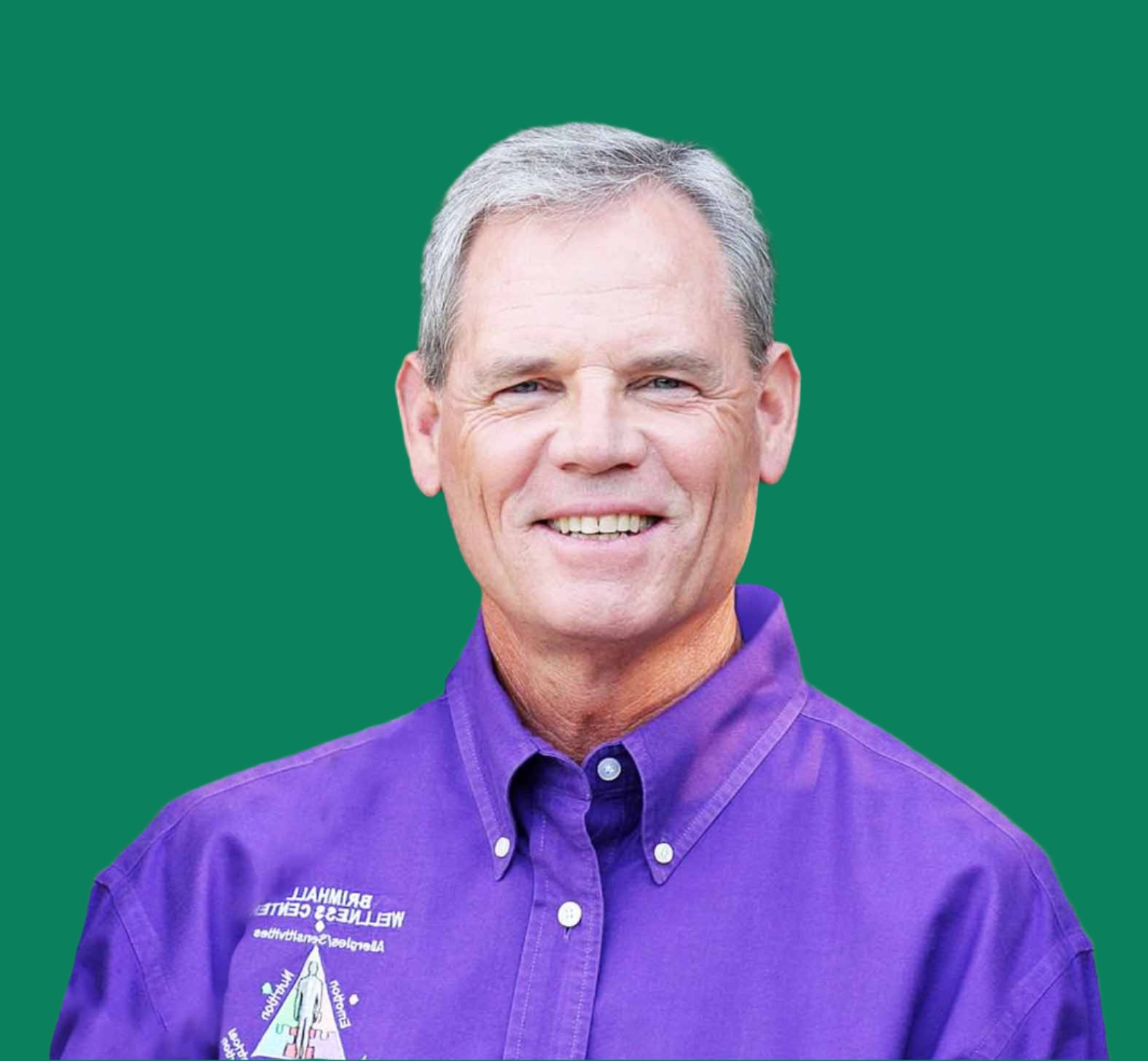 A picture of Dr. John Brimhall in a Purple shirt with a forest in the background.