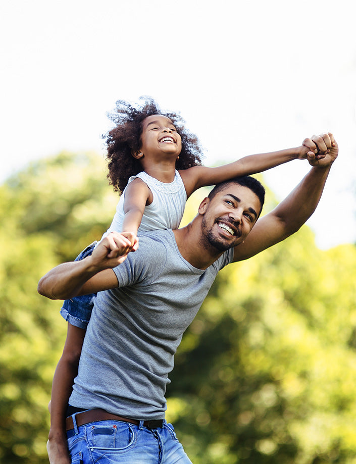 A dad is playing with his daughter. he has her on his back like a piggyback ride as they run around.